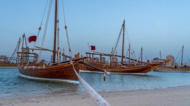 Doha, Katar-22 Ocak 2025: Katar 'ın deniz mirasının simgesel bir sembolü olan geleneksel bir balıkçı teknesi, arka planda Doha silueti ile Basra Körfezi' nin berrak sularında yüzüyor..