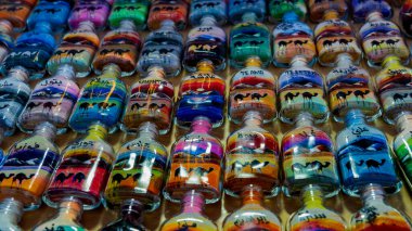 Doha, Katar, 24 Ocak 2025: Canlı kum tabakalarıyla dolu bir cam şişe karmaşık desenler oluşturuyor, sanatsal hassasiyet ve kültür mirası sergiliyor.