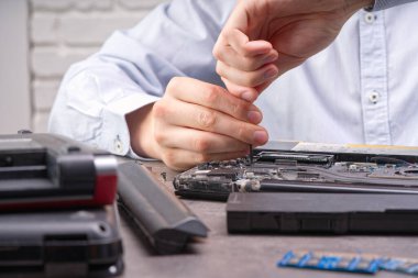 Defter tamiri. Adam dizüstü bilgisayarı söküyor. Klavyeyi kaldırır. Bilgisayar servisi ve tamir konsepti. Onarım atölyesinde dizüstü bilgisayar sökülüyor, yakın plan..