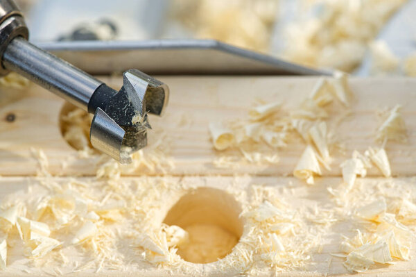 Carpenter builder working overall equals a wooden bar with a milling machine in the workshop.