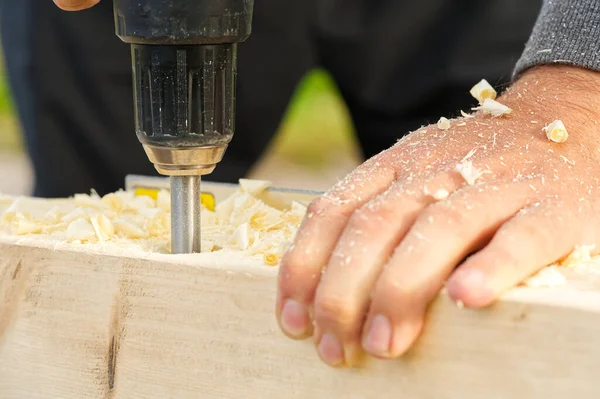 stock image Carpenter drilling holes in the wood beam. wooden frame domestic house building. drilling a hole with a handheld drill