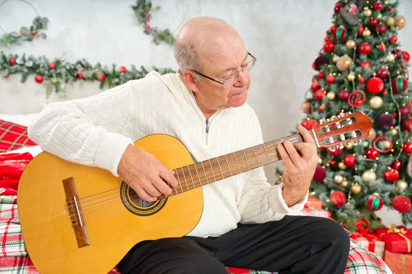 Father playing guitar during christmas. Happy man 60s playing guitar christmas songs. Happy christmas atmosphere.