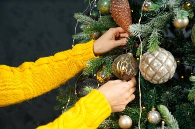 Güzel bir Noel ağacını süsleyen bir kadın. Evinde meyve ağaçlarıyla süslüyor. Yakın plan. Noel tatili ve insanların konsepti. Noel atmosferi