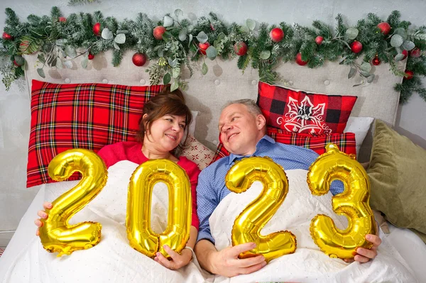 美しいカップルがベッドに寝そべって赤ちゃんを産む予定です クリスマスと幸せな新年は番号2023で願います — ストック写真