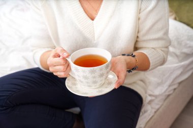 Beyaz kazaklı bir kız elinde bir fincan sıcak kahve ya da bir Noel ağacının arka planında çay tutuyor. Sıcak Noel atmosferi. Noel için alkolsüz sıcak bir içki. Yaşam biçimi