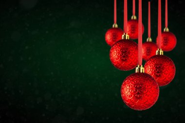 Kırmızı Noel ağacı süslemeleri fotokopi alanından sarkıyor. Soyut koyu yeşil arka planda asılı cam veya plastikten yapılmış Noel topları.