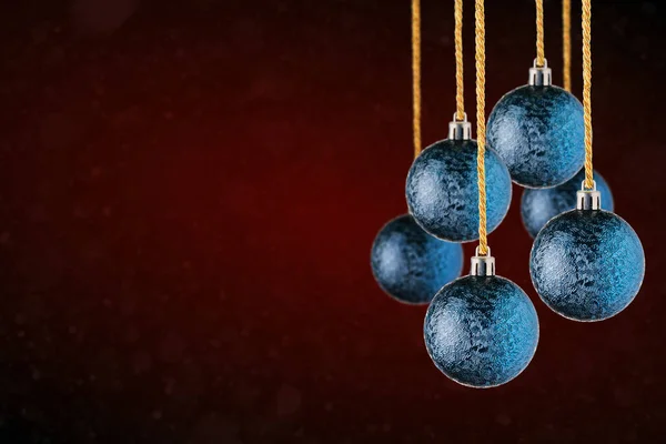 Red Christmas tree ornaments hanging with copy space. Christmas Balls made of glass or plastic hanging over abstract dark blue background.