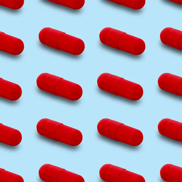 Gel capsule seamless pattern. Red capsule shaped medicine. pharmacy concept. food supplement. Capsule pills pattern on a light blue background