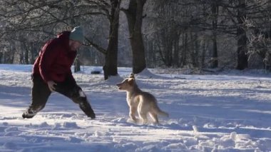 A happy Man walking dog at snowy weather, outdoor. dog owner playing with puppy winter concept. Playing with happy dog fun
