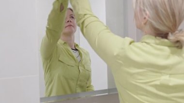 cleaning company. hotel maid microfiber cloth washing cleaning a mirror. household service concept. woman cleaning mirror in bathroom