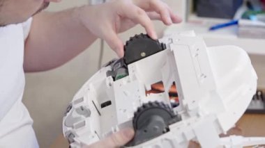 Robot elektrik süpürgelerinin onarımı ve bakımı. Çipi lehimlemek için parçalanmış elektrikli süpürge. Tamirci obotik elektrik süpürgesi tamir ediyor..