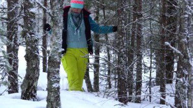 Kışın kalın ceketli bir kadın, karlı kış ormanlarında yürüyor. Genç bir kadın muhteşem bir kış ormanında yürüyor.