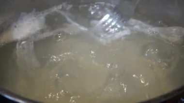 Boiling rice in portion bag. A bag of white, cooked rice is held with a hand in front of a dark background.