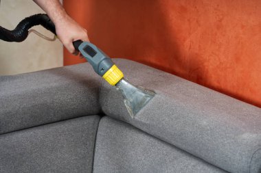 Sofa chemical cleaning with professionally extraction method. Wet textile sofa cleaning. home cleaning service. cleaning sofa with washing suction cleaner closeup. clipart