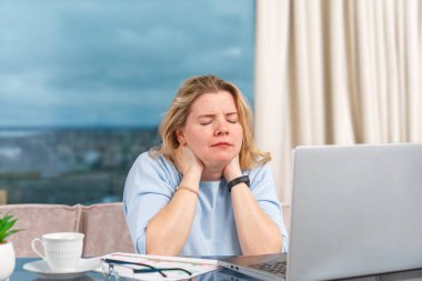Evdeki bilgisayarla çalışan mutsuz, yorgun kadın. Stres, depresyon, yalnızlık, yorgunluk, tükenme konsepti. İş kadını bilgisayarda çalışıyor, kendini kötü hissediyor, stres ve baş ağrısı çekiyor..