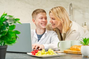 Happy mother and son have healthy breakfast in the kitchen at home. Happy mother and son in the kitchen. breakfast and digital devices Concept of happy family and healthy food.
