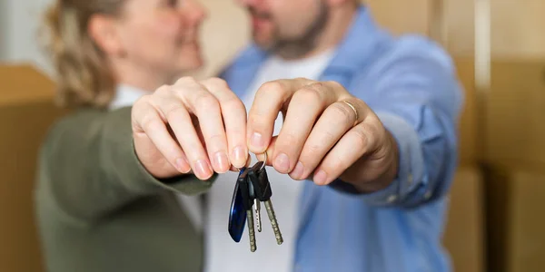 Couple showing keys to new apartment. real estate mortgage, loan concept. moving in new house. Young smiling couple holding their new house keys. first own apartment or house.