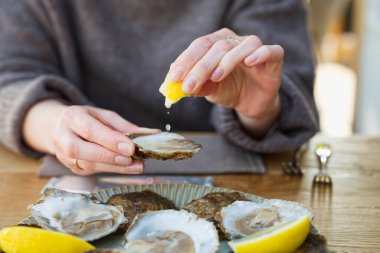 Güzel kadın taze istiridye yiyor ve restoranda içiyor. Deniz ürünleri lezzetleri. Limonlu istiridye