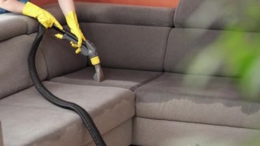 Temizlik konsepti. Kadınlar oturma odasında yumuşak mobilyaları yıkarlar. Çalışan mobilyalardan toprağı temizliyor, yakın plan.