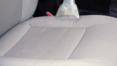Tamirci arabanın ön tekstil koltuğunu elektrikli süpürgeyle süpürüyor. Adam temizleme işi Minivan.