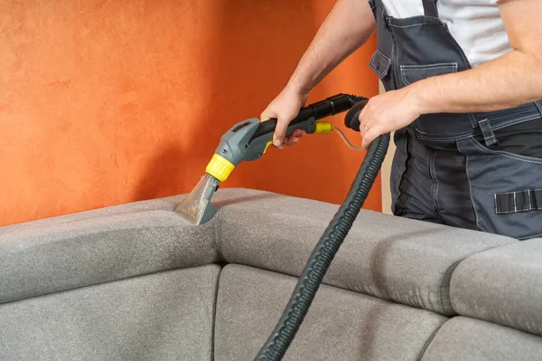 stock image Dry cleaners man employee removing dirt from furniture in flat, closeup, vacuum clean sofa with professional equipment. cleaning sofa with washing suction cleaner closeup.