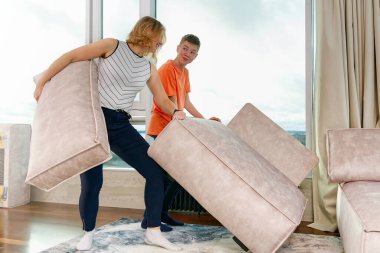 family rearranging furniture. Happy couple moving furniture in new apartment. Moving day, happy buyers. Positive smiling young couple moving furniture