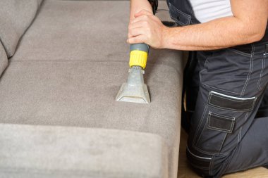 Kuru temizlemeci çalışanı mobilyalardaki toprağı temizliyor, yakın plan, elektrikli süpürge ile profesyonel ekipmanla temizliyor. Kanepeyi yıkama temizliği ile kapatıyoruz..
