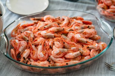 Tabaklı bir yemek masasında soyulmamış karides tabağı. Deniz ürünleri lokantası. Haşlanmış karides. Vejetaryen yemeği, yemek.