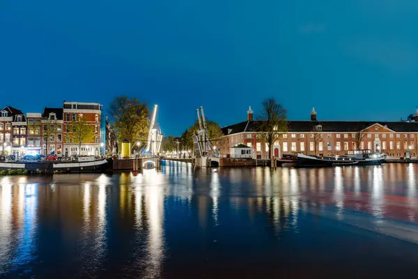 stock image Illuminated Canals and Riverside Delights: Exploring Amsterdam After Dark. Captivating Cityscape of Amsterdam at Night: A Delightful Blend of Tradition and Modernity