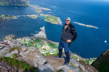 Rahatlamış yürüyüşçü, Lofoten adalarının, fiyortların, Norveç 'in Reinebringen tepelerinde nefes kesici manzaralardan hoşlanır. Seyahat eden adam Norveç dağlarını seyrediyor Seyahat yaşam tarzı konsepti macerası aktif