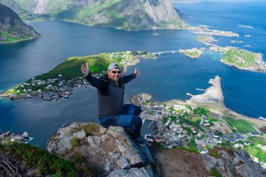 Rahatlamış yürüyüşçü, Lofoten adalarının, fiyortların, Norveç 'in Reinebringen tepelerinde nefes kesici manzaralardan hoşlanır. Seyahat eden adam Norveç dağlarını seyrediyor Seyahat yaşam tarzı konsepti macerası aktif