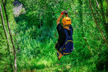 Heyecan verici bir halatla kayma deneyiminin tadını çıkaran, Aktivite Dolu Tatilin Eğlencesini Kucaklayan ve Sersemletici Turizm Bakışları