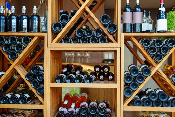 A tastefully designed wooden wine rack elegantly showcases an array of exclusive and pricey wines, perfect for creating a luxurious and sophisticated atmosphere.
