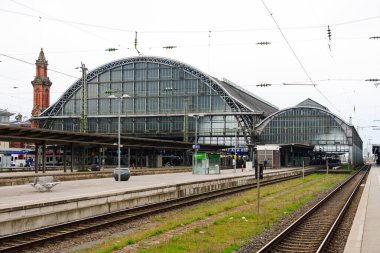 Bremen Merkez Tren İstasyonu 'ndaki hareketli platformların manzarasında istasyonun mimari güzelliği ve modern altyapısı arasında trenlerini bekleyen yolcular görülüyor..
