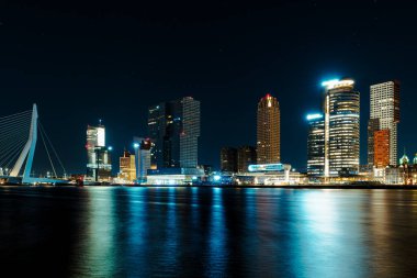 Rotterdam şehrinin büyüleyici bir gece manzarası yıldızlı bir gökyüzünün arka planına karşı modern gökdelenini sergiliyor büyüleyici ve büyüleyici bir şehir manzarası yaratıyor..