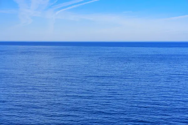 Capture the serenity of a deep blue ocean meeting an endless clear sky, perfect for promotional purposes, product placement, and ad campaigns.