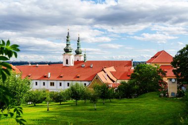 Bereketli yeşil tepelerin arasına yuva yapmış, turizm veya turizmle ilgili projeler için ideal, açık mavi bir gökyüzü ve tüylü beyaz bulutlarla tamamlanmış büyüleyici kırmızı çatıları olan Avrupa köyü..
