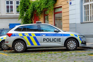 Temmuz 2024, belirgin mavi ve sarı çizgili bir polis arabası bir binanın yakınına park edilmiş. Bu görüntü polis, kolluk kuvvetleri ve kamu güvenliği konuları için uygundur..