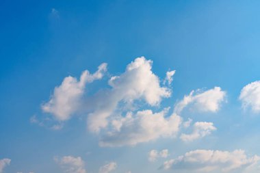 Gökyüzü parlak bir mavi, kabarık beyaz bulutlarla süslenmiş, geniş alanda tembelce sürüklenen. Güneş sıcak bir parıltı yayıyor, açık hava aktivitelerini davet ediyor ve sakin bir atmosfer yaratıyor..