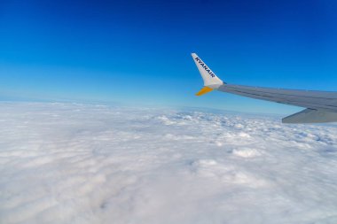 Tallinn, Estonya, 30.03.2024 - Beyaz bulutların üzerinde bir kanadın yer aldığı, seyahat ve maceranın özünü yakalayan, seyahat tutkunları için mükemmel bir uçak manzarası.