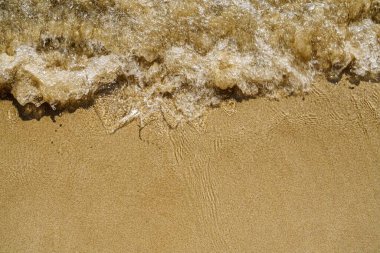 Kıyı şeridinin sakinliğini bu görüntüyle yakalayın. Altın bir kumsalın üzerinde yavaşça süzülen bir dalga. Rahatlama ve kıyı kaçışı çağrıştırıyor..