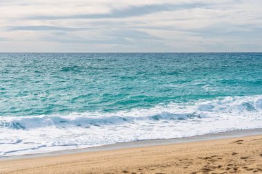 Bu güzel deniz manzarası, huzurlu okyanusun kıyıya kavuşmasını gösteriyor. Turkuaz su, beyaz dalgalar ve altın kumla rahatlamayı çağrıştırıyor ve kıyı temaları için mükemmel..