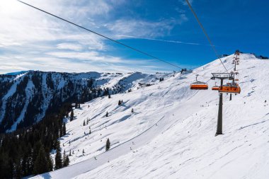 Bir kayak merkezinde güzel bir kış sahnesi, açık mavi bir gökyüzünün altında kar kaplı bir dağa giden bir asansörle. Seyahat promosyonları ve kış sporları reklamları için harika..