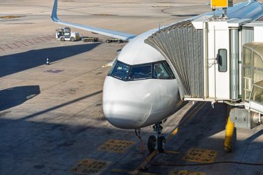 Şık bir uçak havaalanı kapısına yanaşıyor, yolcu alımına hazırlanıyor. Bu görüntü, seyahatin heyecanını ve modern hava taşımacılığının verimliliğini simgeliyor..