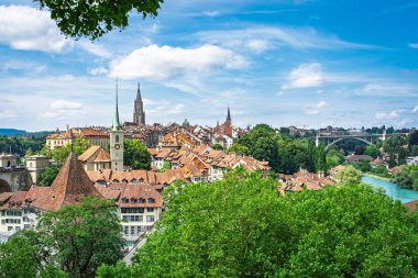Bern, İsviçre 'nin güzelliğini keşfedin, tarihi mimarisi, sakin nehri ve berrak bir yaz gökyüzüne karşı kurulmuş yemyeşil alanları ile birlikte. Seyahat promosyonları için mükemmel..
