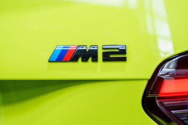 Munchen, Almanya, 29.06.2024 - canlı sarı bir arabanın BMW M2 amblemine yakın çekim. Bu amblem otomotiv endüstrisinde yüksek performansı ve modern tasarımı simgeler..