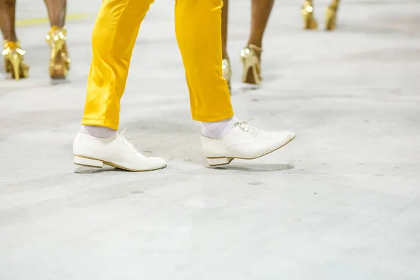 legs of a sambista dancing, with yellow pants and white shoes at the sambodromo da marques de sapucai in Rio de Janeiro, Brazil.