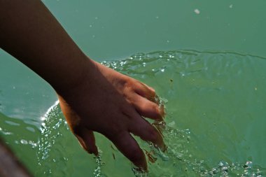 Çocuk kayıkla gezerken nehir suyunun tadını çıkarıyor.