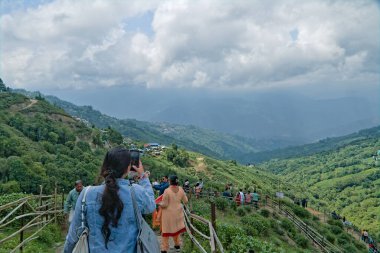 Darjeeling, Batı Bengal, Hindistan - 05.26.2023 turist Darjeeling Hill istasyonundaki manzaralı çay bahçesinin parlak güneşli bir günde fotoğraflarını çekiyor.