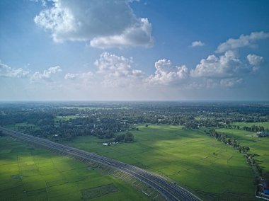 09.16.2023. Raiganj Batı Bengal Hindistan. Yeşil tarım arazisinden geçen ulusal otoyolun en üst hava manzarası